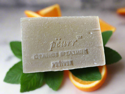 Bar of soap with 'peurr' branding on a bed of orange slices and spearmint leaves.