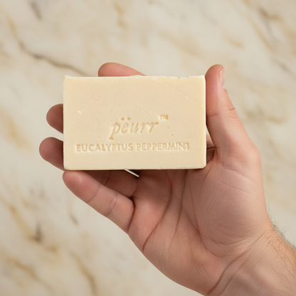 Eucalyptus & Peppermint soap held in a man’s hand against warm marble