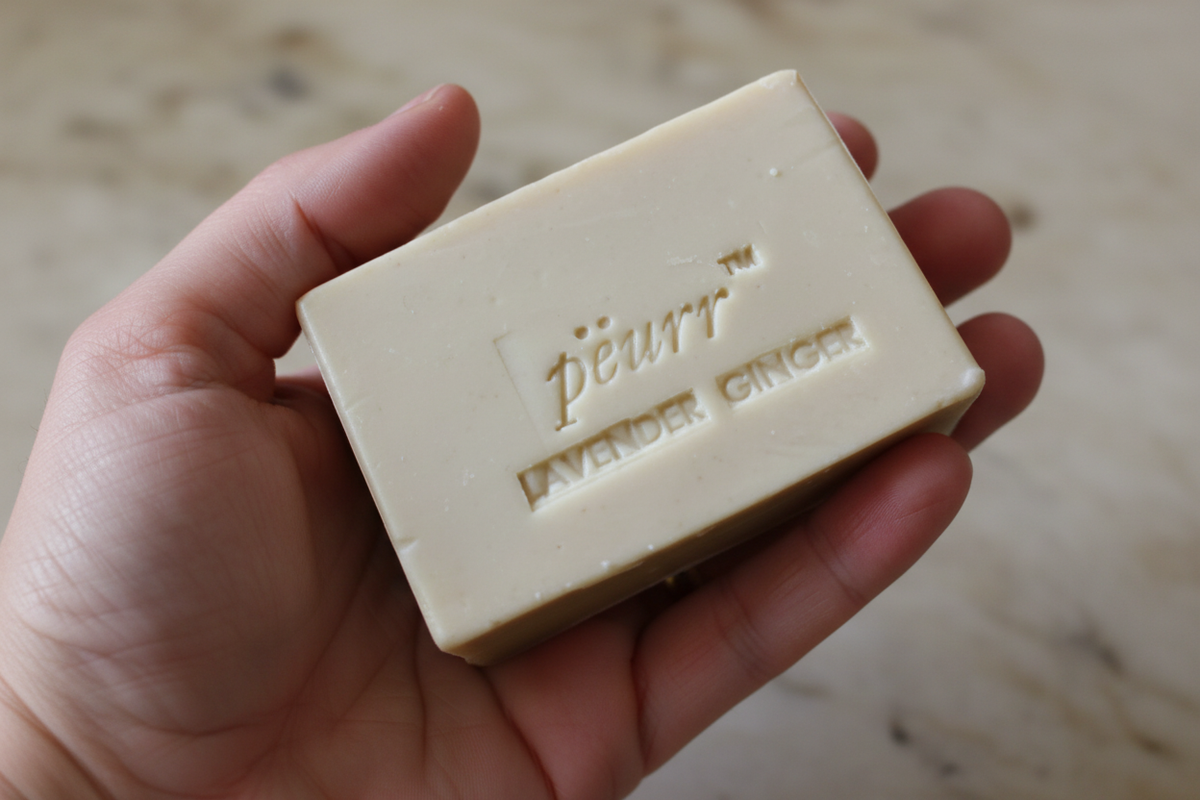PËURR® Lavender & Ginger soap held naturally in a hand against warm marble