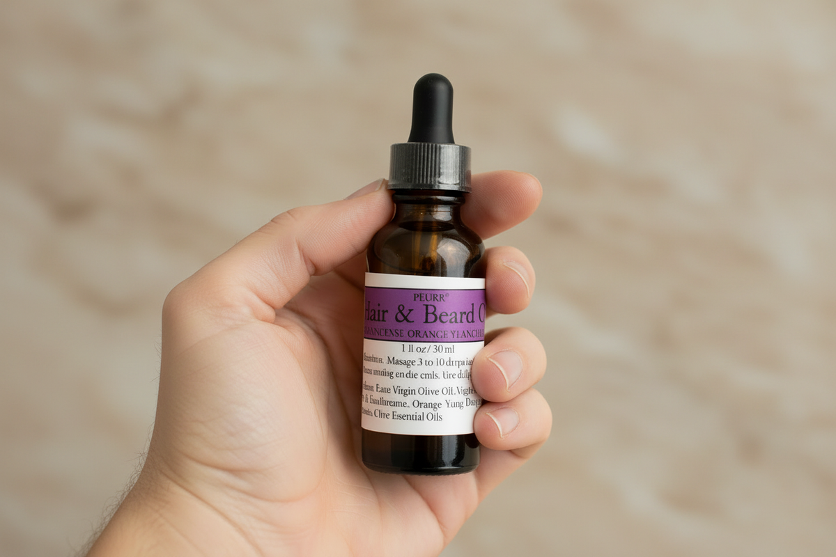 PËURR® Purple Label Hair & Beard Oil held in a hand against a matching marble background

