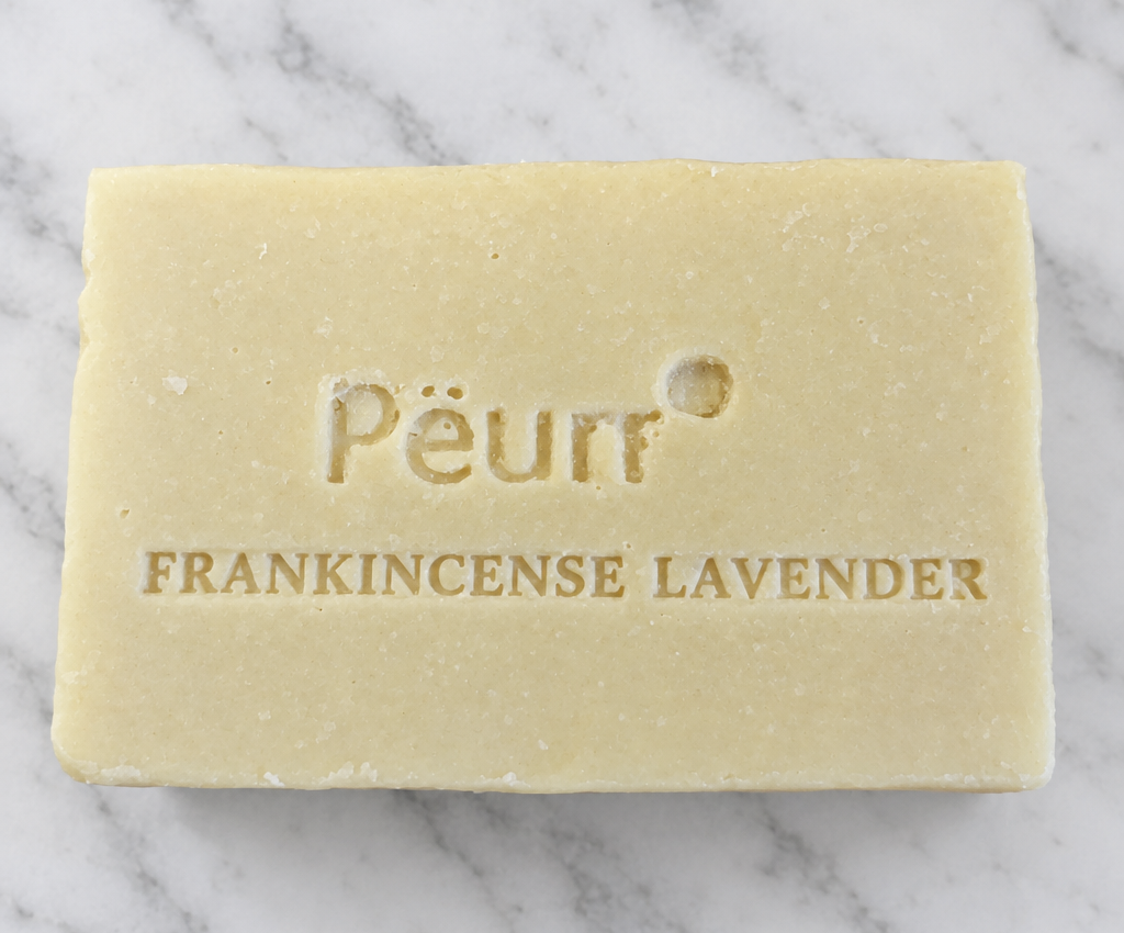 PËURR® Frankincense Lavender olive oil and goat milk soap bar with embossed lettering on white marble.