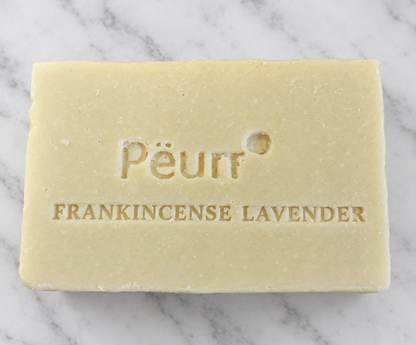 PËURR® Frankincense Lavender olive oil and goat milk soap bar with embossed lettering on white marble.