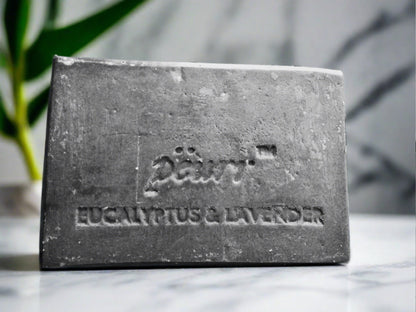 A bar of CHARCOAL Eucalyptus & Lavender Goat Milk & Olive Oil Soap with the brand name PÈURR engraved on it.