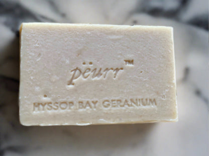 A bar of Hyssop Bay Geranium Goat Milk and Olive Oil Soap with 'PÈURR MYSSOP BAY GERANIUM' stamped on the top.
