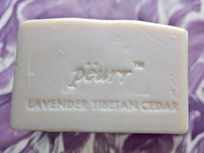 A bar of PÈURR brand soap with 'LAVENDER TIBETAN CEDAR' engraved on it, against a purple background.