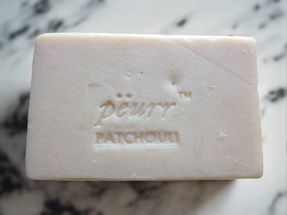 A bar of Patchouli Goat Milk & Olive Oil Soap with the brand name 'Pëurr' and the word 'PATCHOULI' embossed on the top.