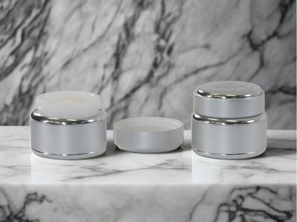 Two jars of body butter, one with lid off on marble surface