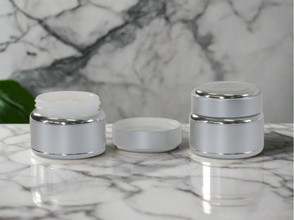 Two jars body butter one with lid off against marble background
